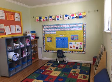 Classroom with colorful rug, bulletin board, and cubbies