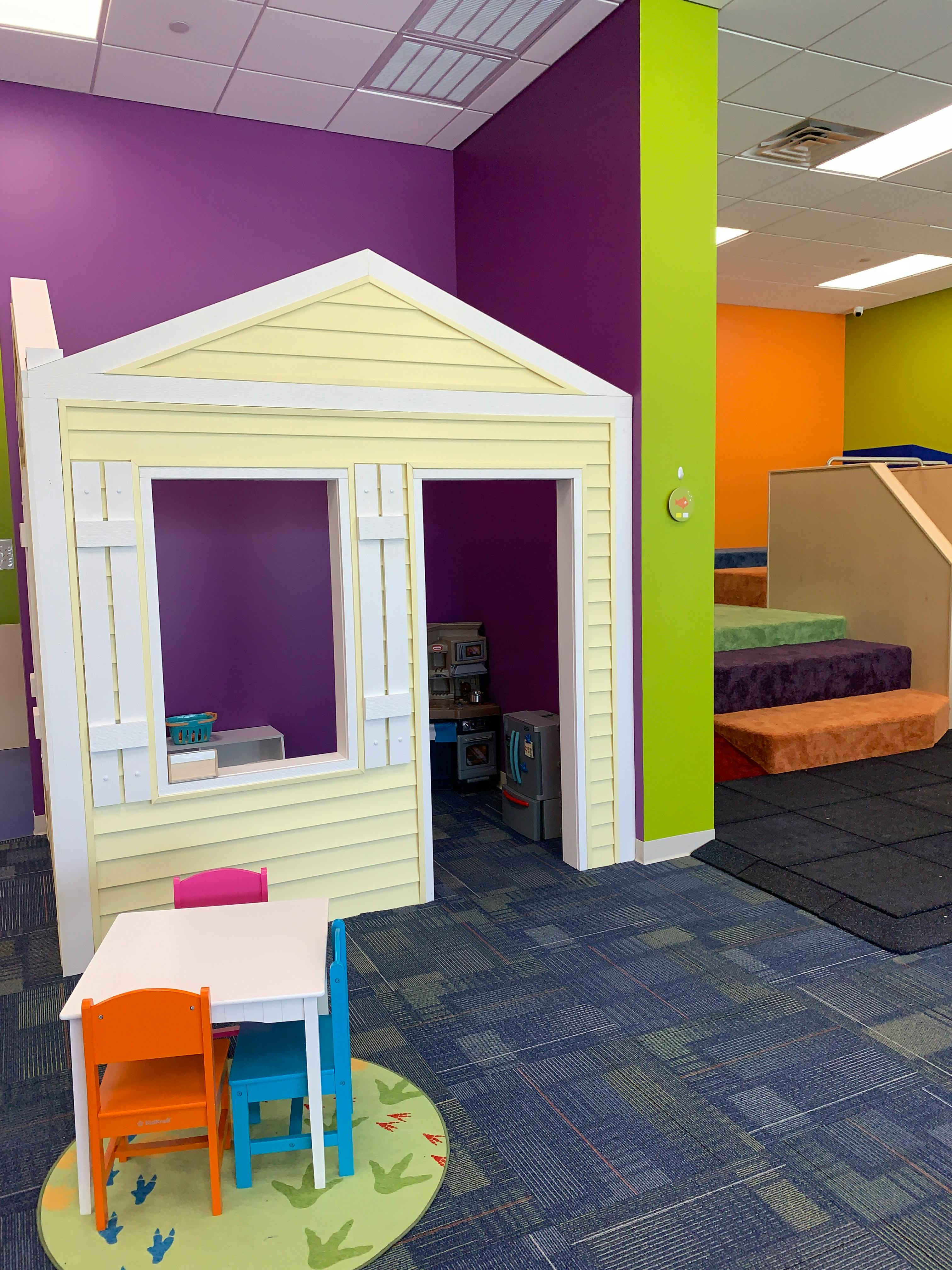 Playhouse with a small table and chairs in a children's play area