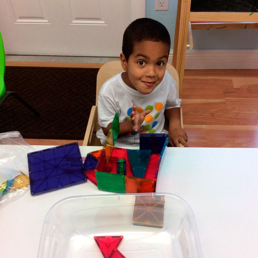 Child sitting at a table with colorful magnetic tiles