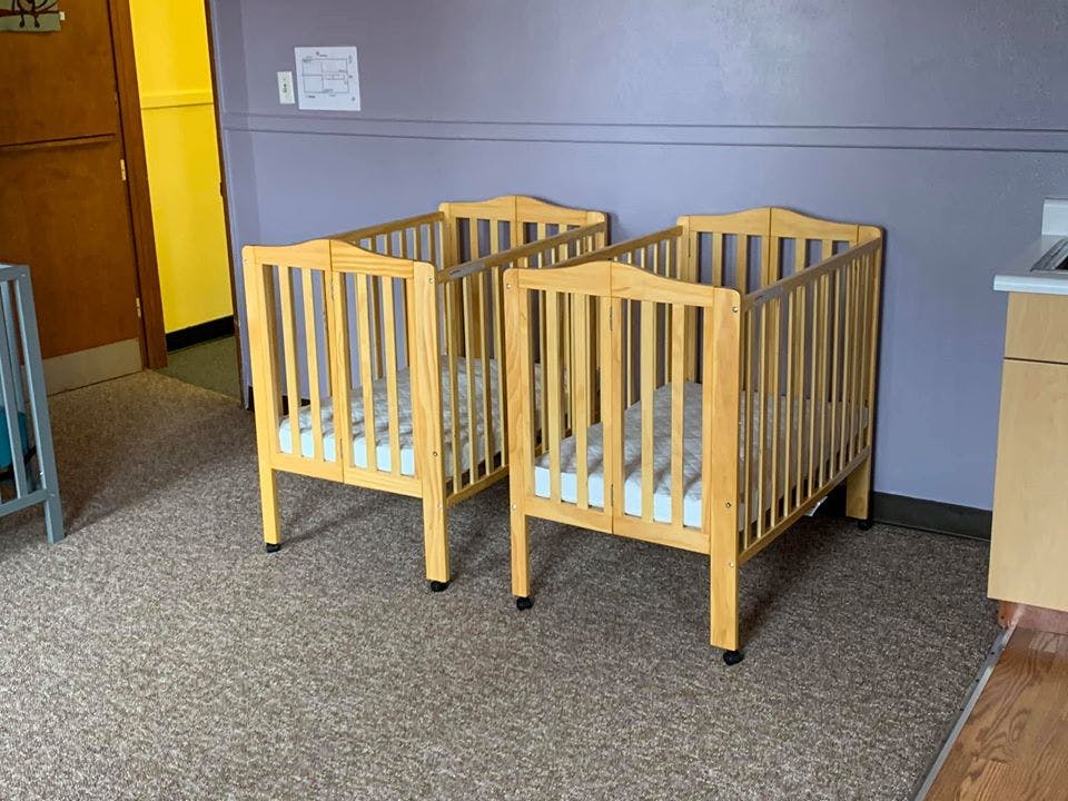 Two wooden cribs with mattresses in a room