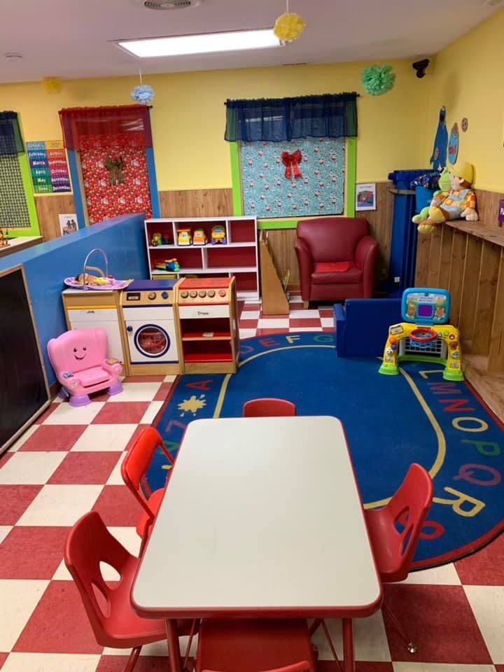 Playroom with small table and chairs, toy kitchen, and alphabet rug