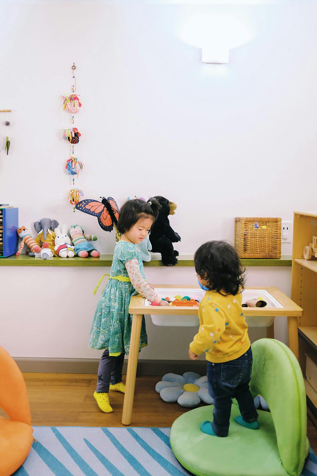 Two children playing together at a table in a playroom