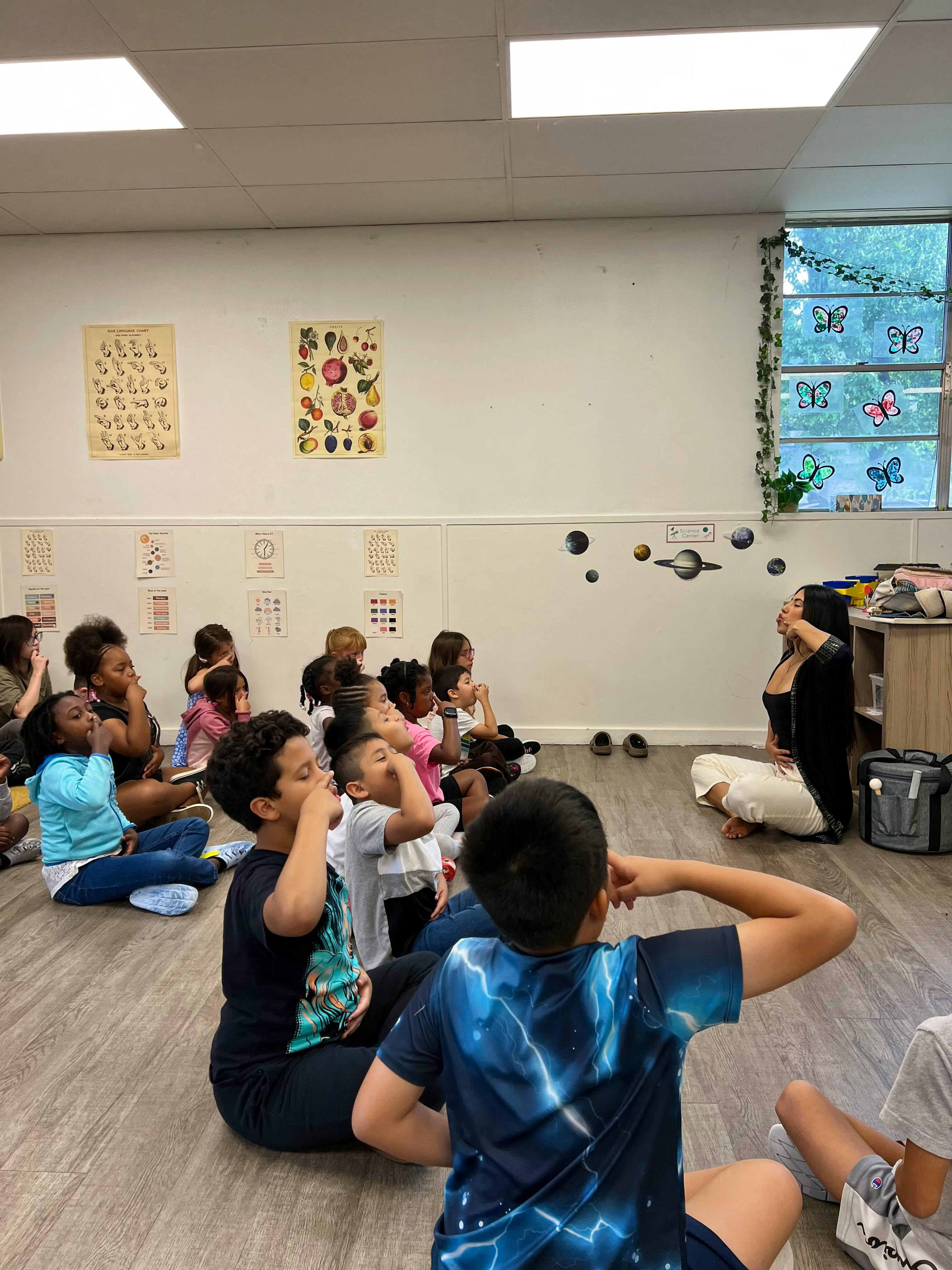 Adult and children sitting on floor in classroom
