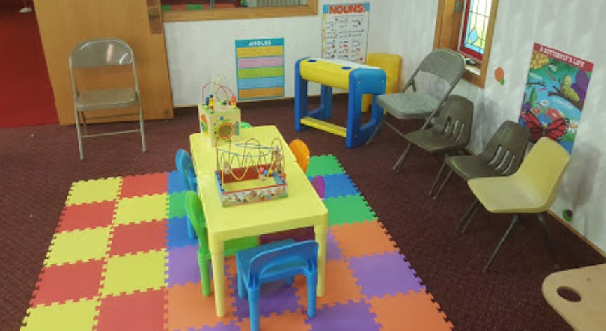 Children's play area with a yellow table, chairs, and colorful floor mats