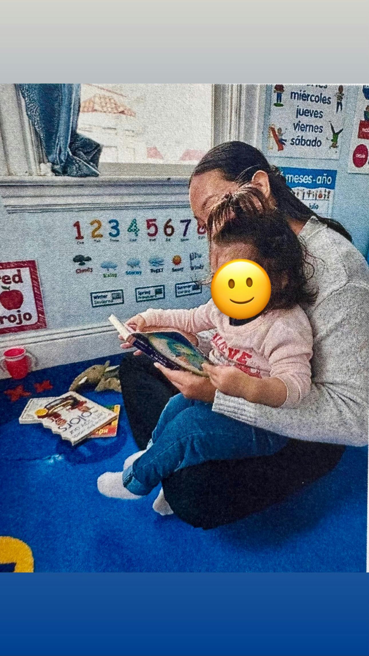 Person and child sitting on floor reading a book