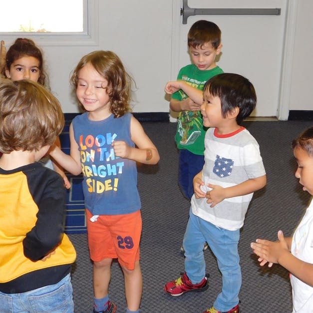 Children standing and interacting in a room
