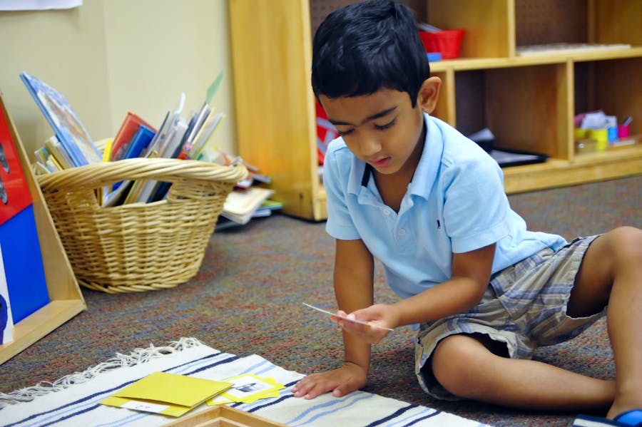 Child sitting on floor looking at a small card in a classroom