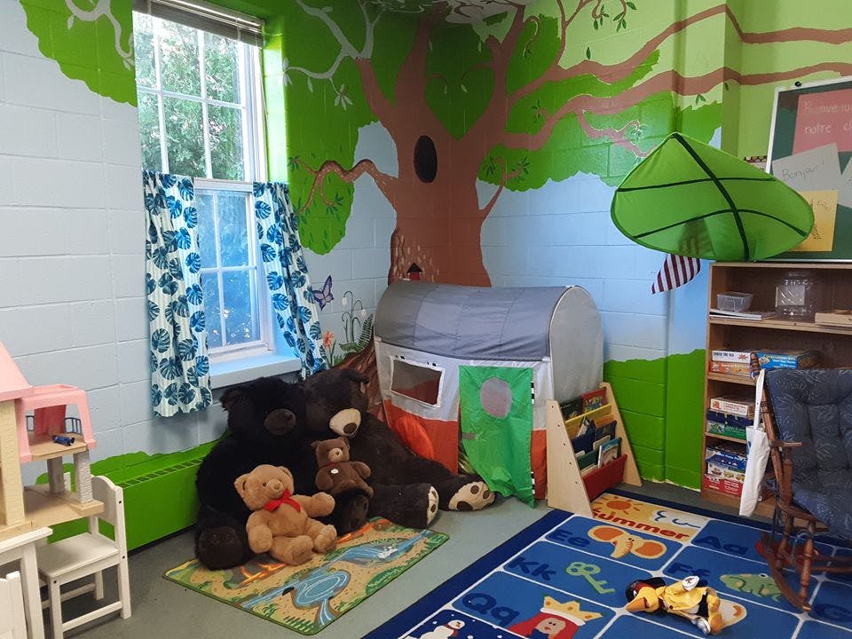 Playroom with stuffed bears, play tent, and tree mural