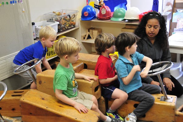 Adult and children playing with wooden blocks and toy steering wheels
