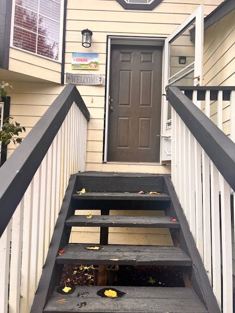 Stairs leading up to a brown door with a welcome sign