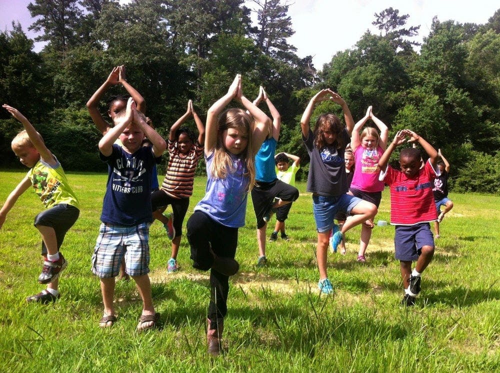 Group of children doing yoga poses outdoors