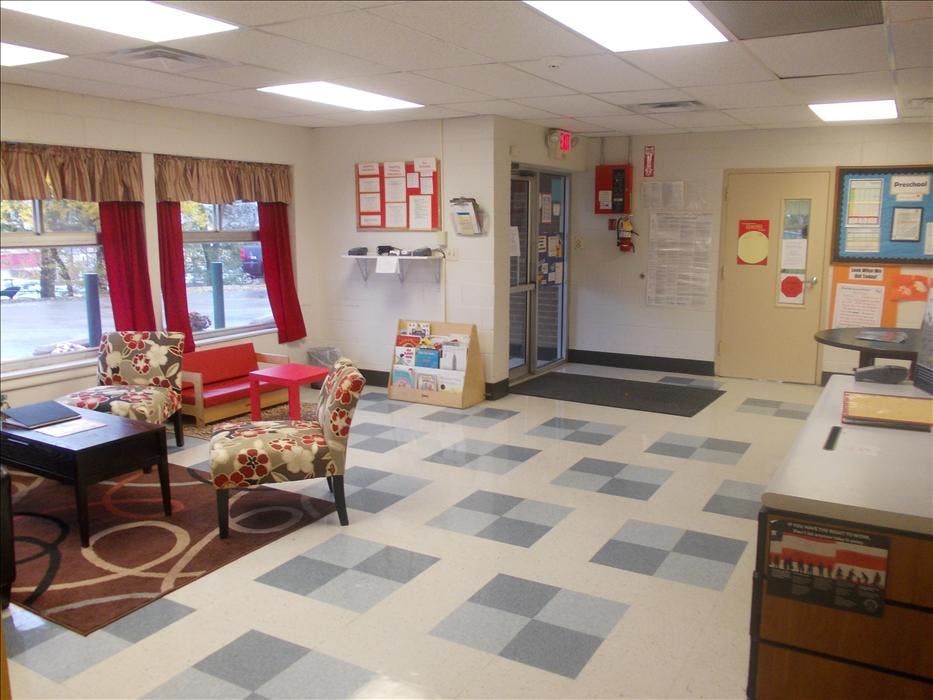 Lobby area with seating, patterned floor, and windows with bulletin boards and doors in background