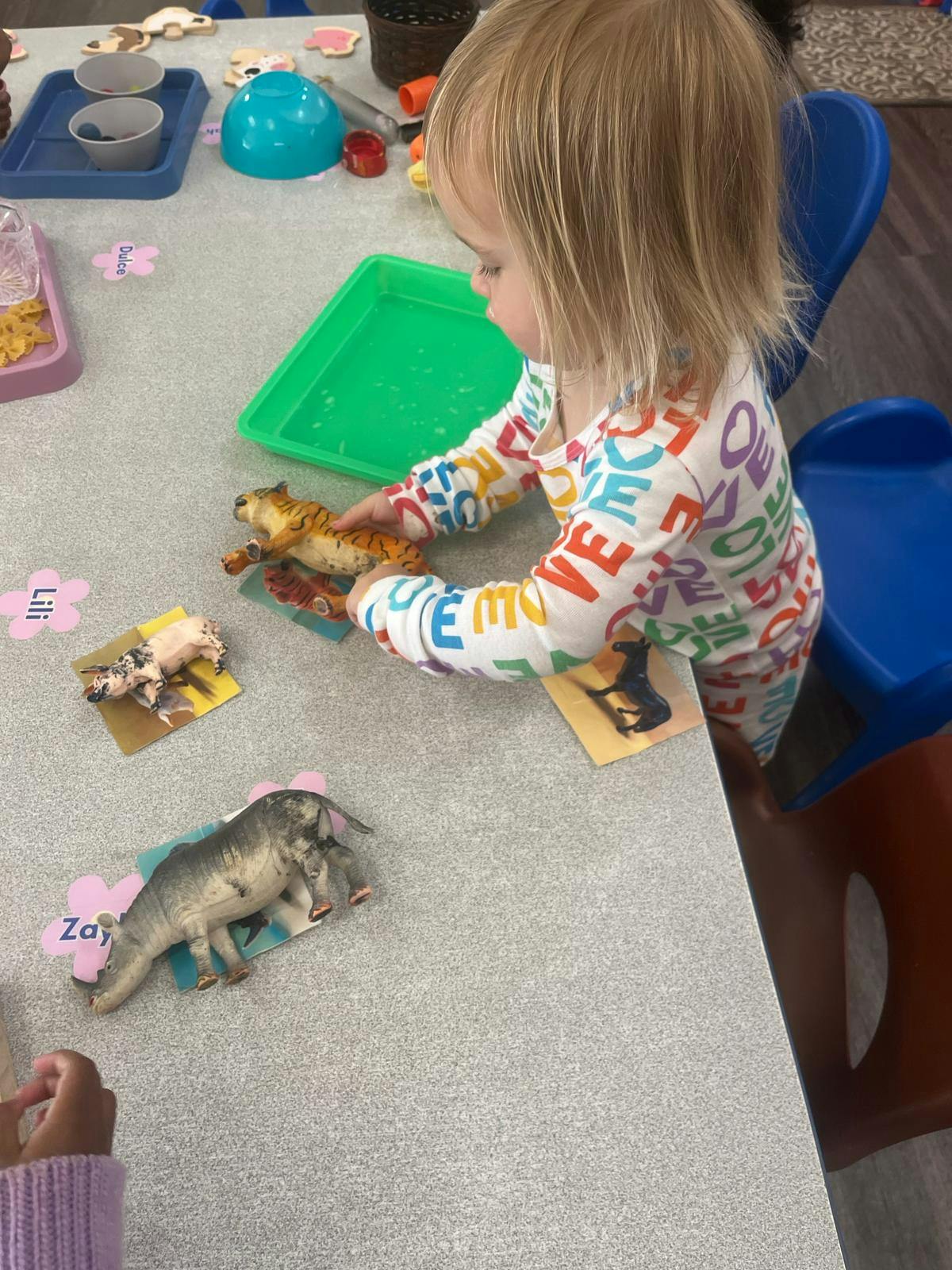 Child playing with animal figurines on a table