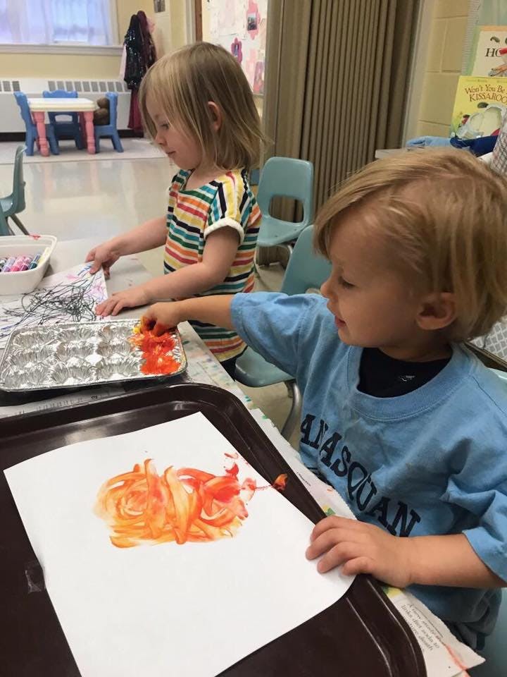 Two children finger painting at a table