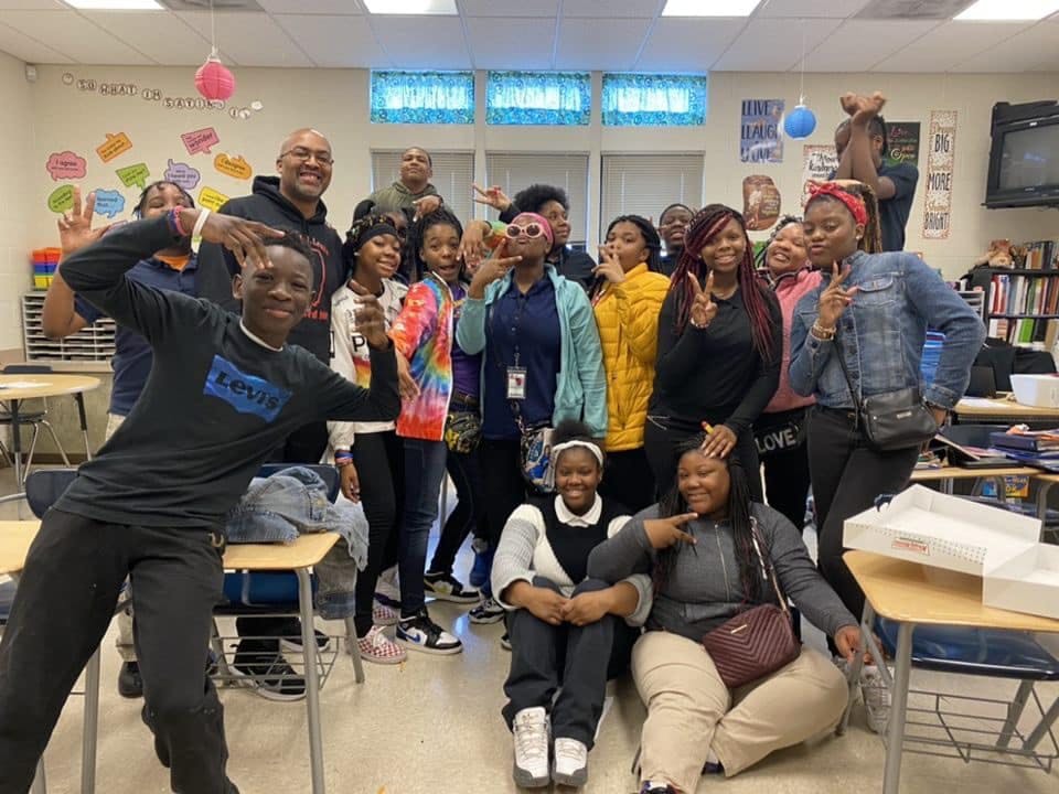 Group of people and teens posing in a classroom