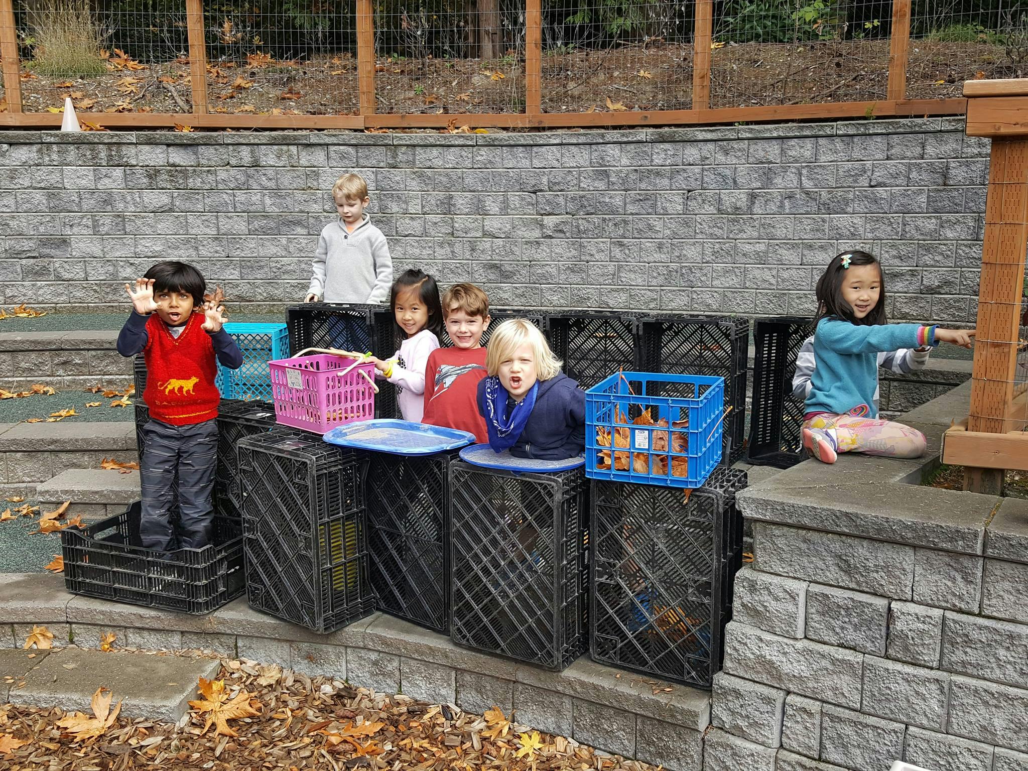 Children playing with crates and baskets outdoors
