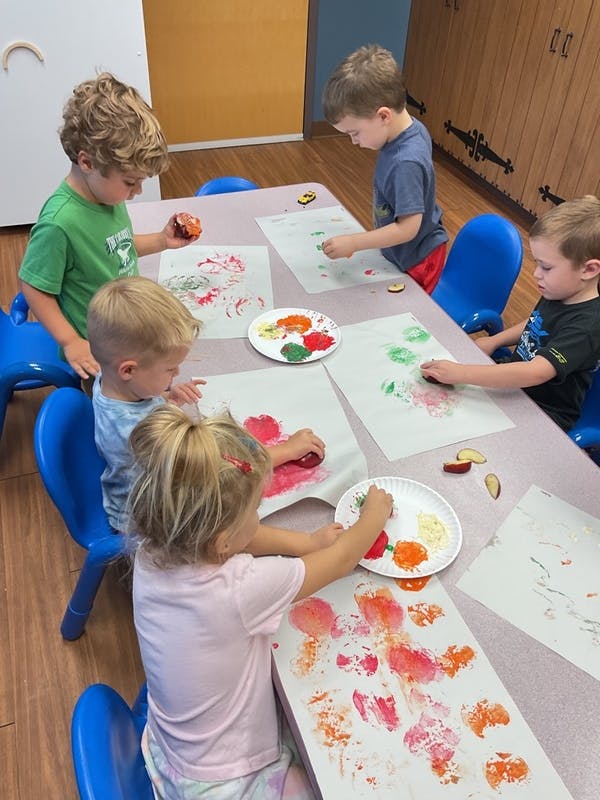 Children doing apple printing art in a classroom
