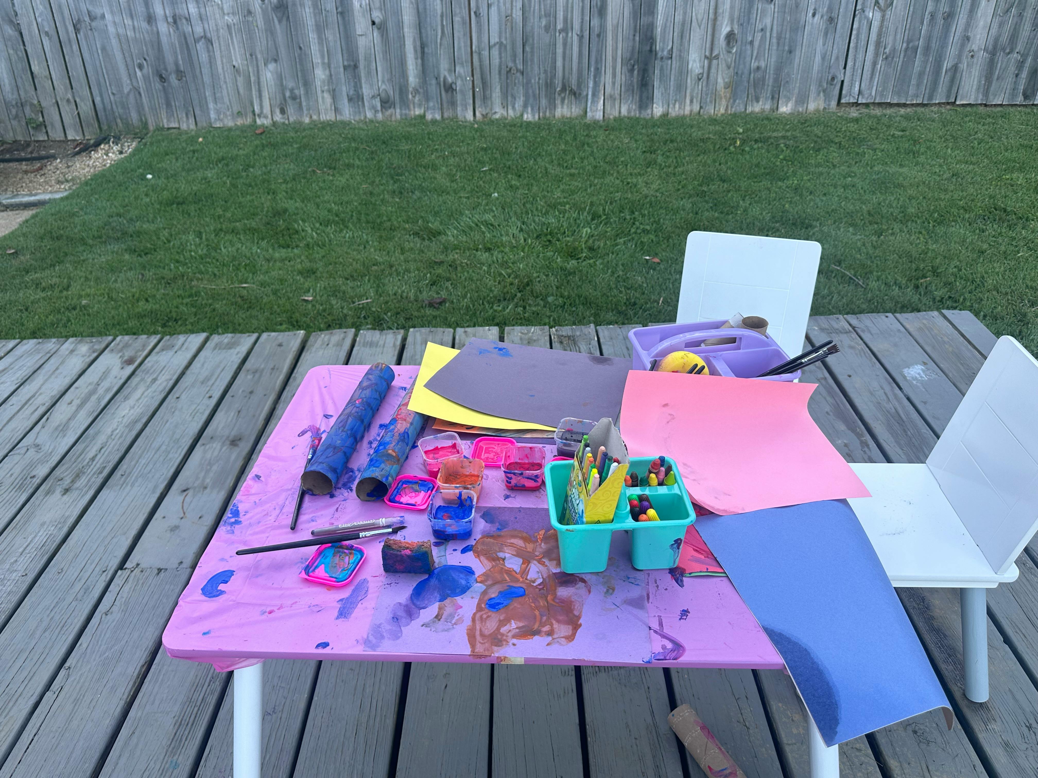 Craft supplies on a table with paint, paper, and brushes