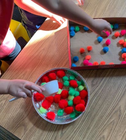 Child's hands playing with colorful pom-poms