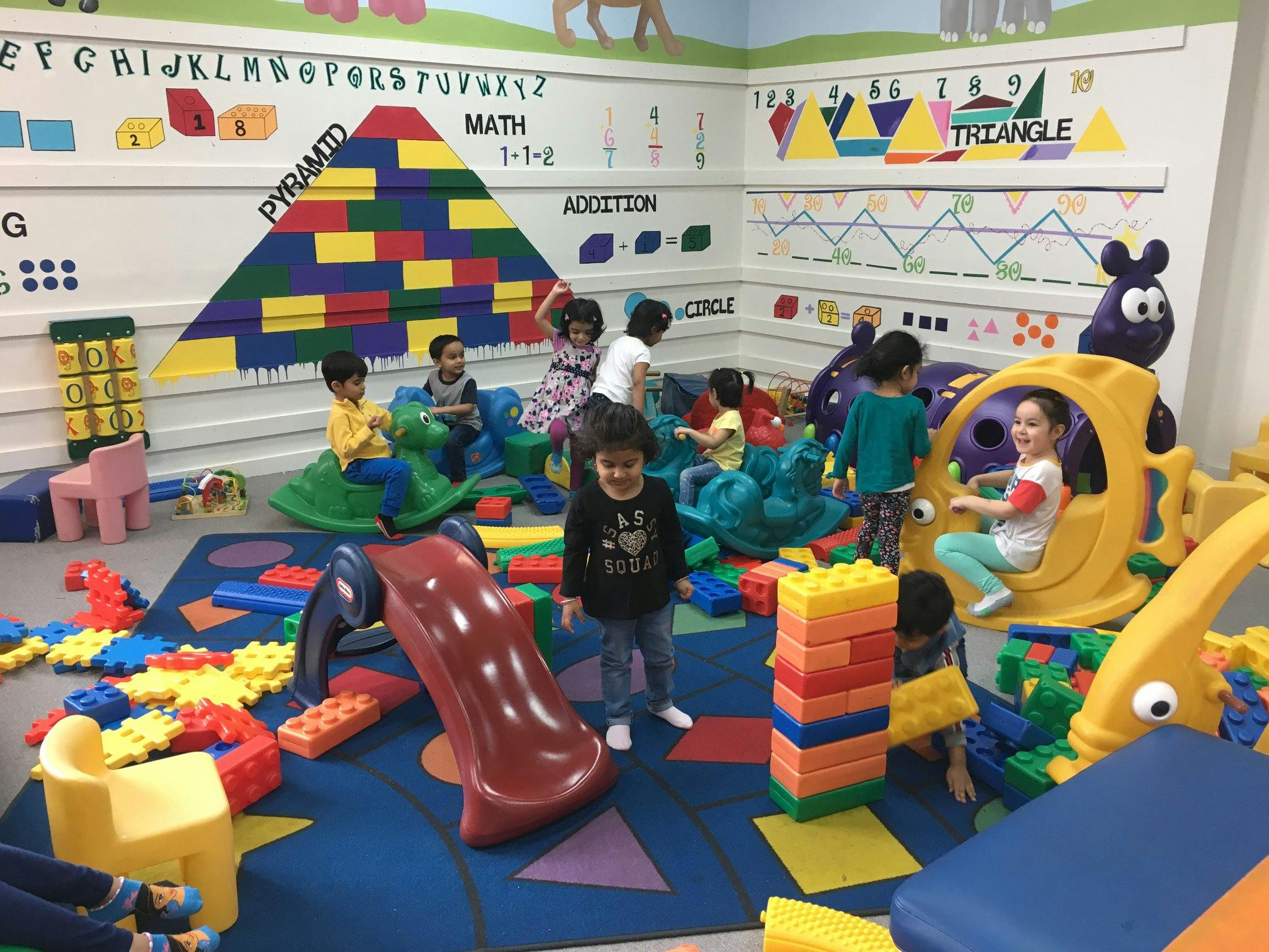 Children playing in a colorful room with toys and a slide