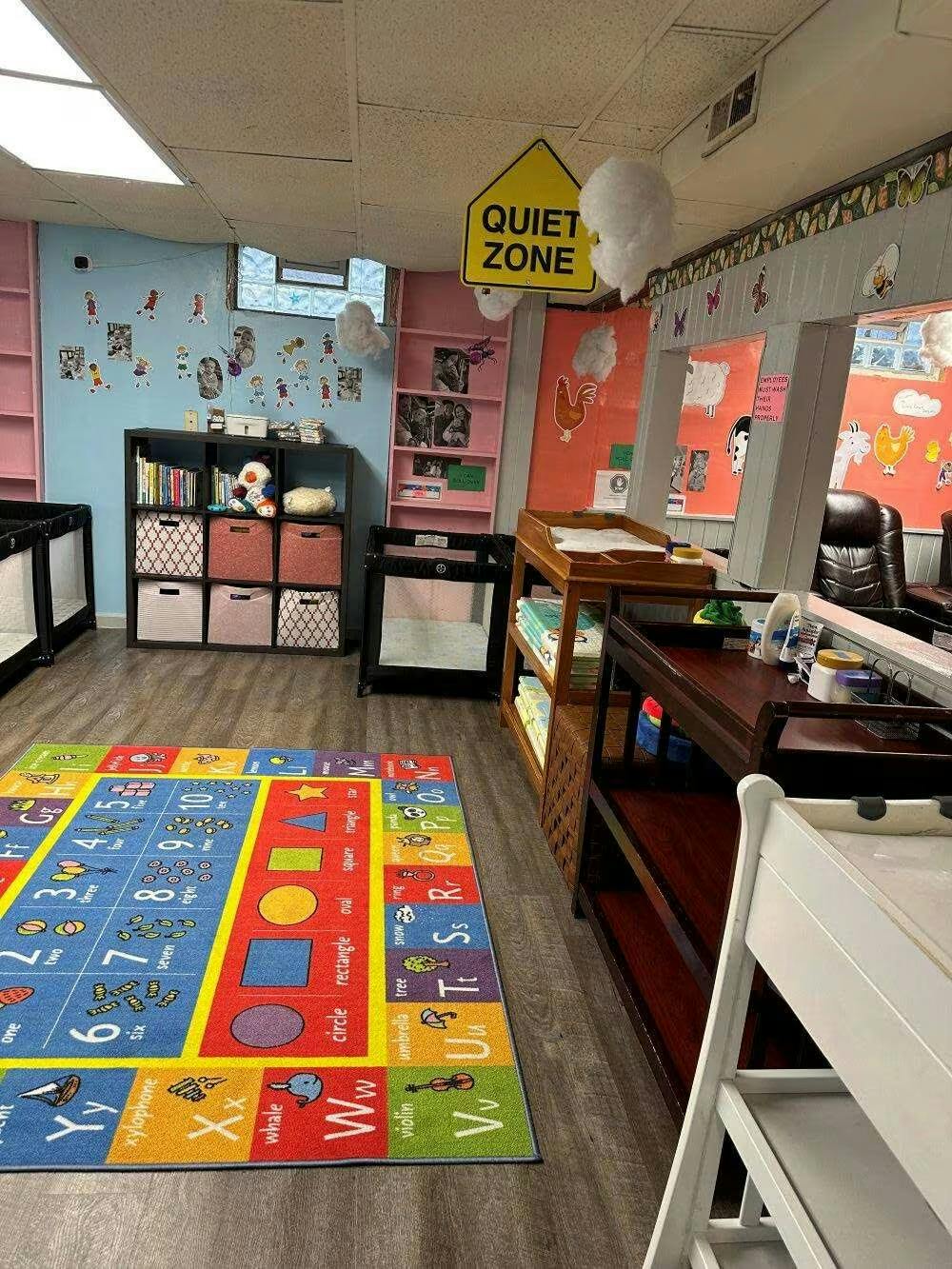 Childcare room with play mats, cribs, and educational wall decor
