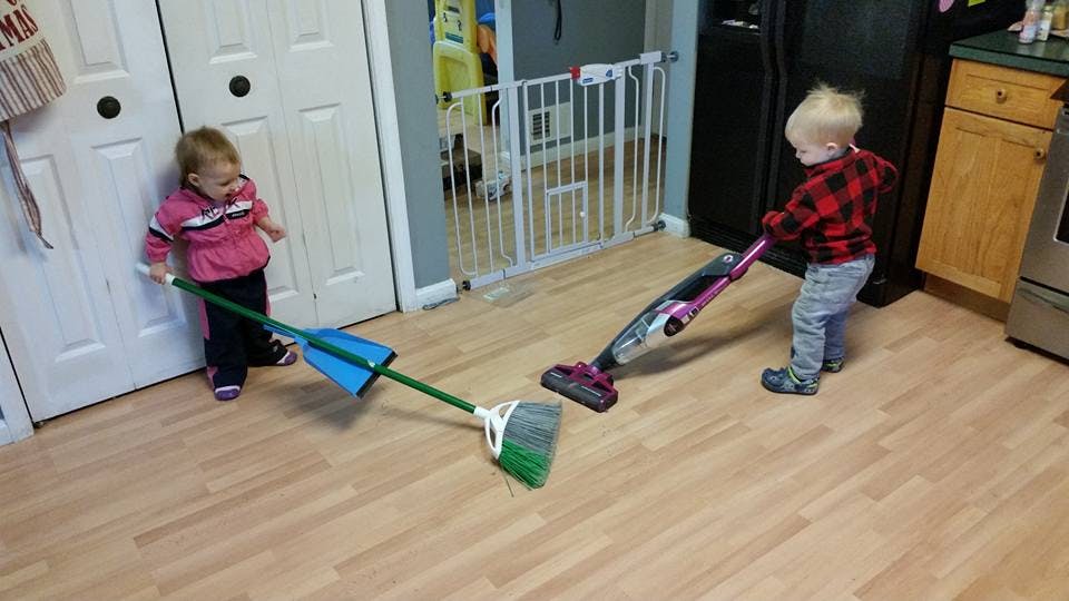 Two children sweeping and vacuuming a floor