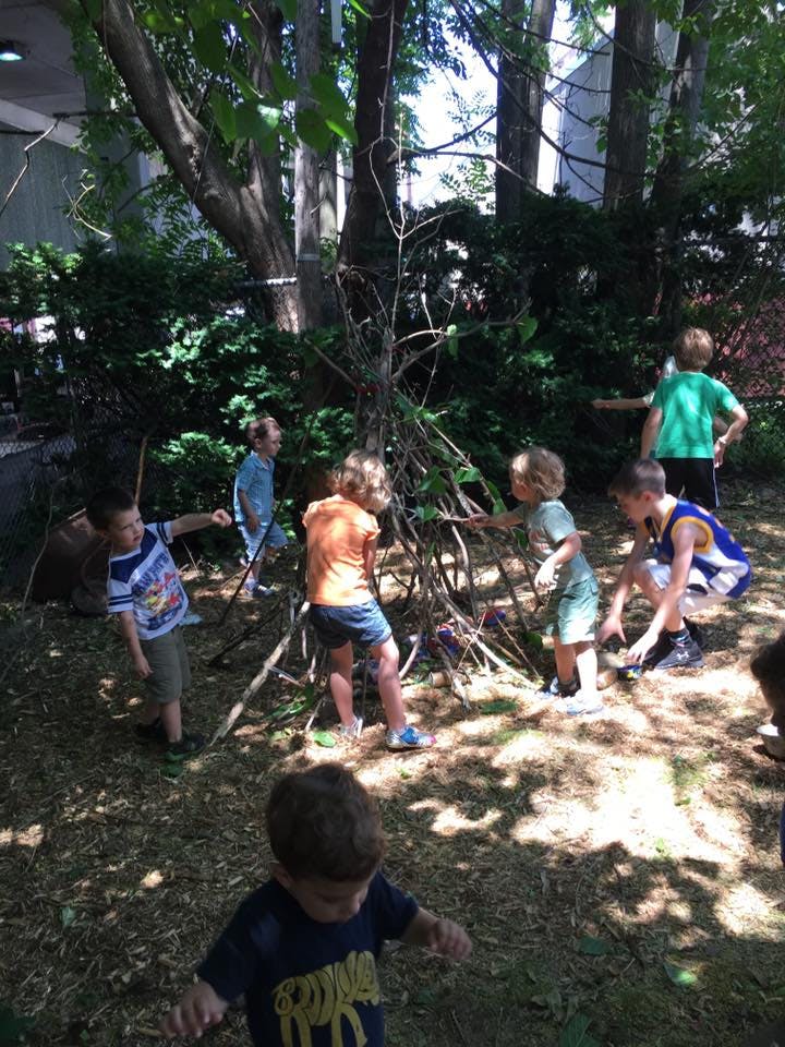 Children playing around a stick structure outdoors