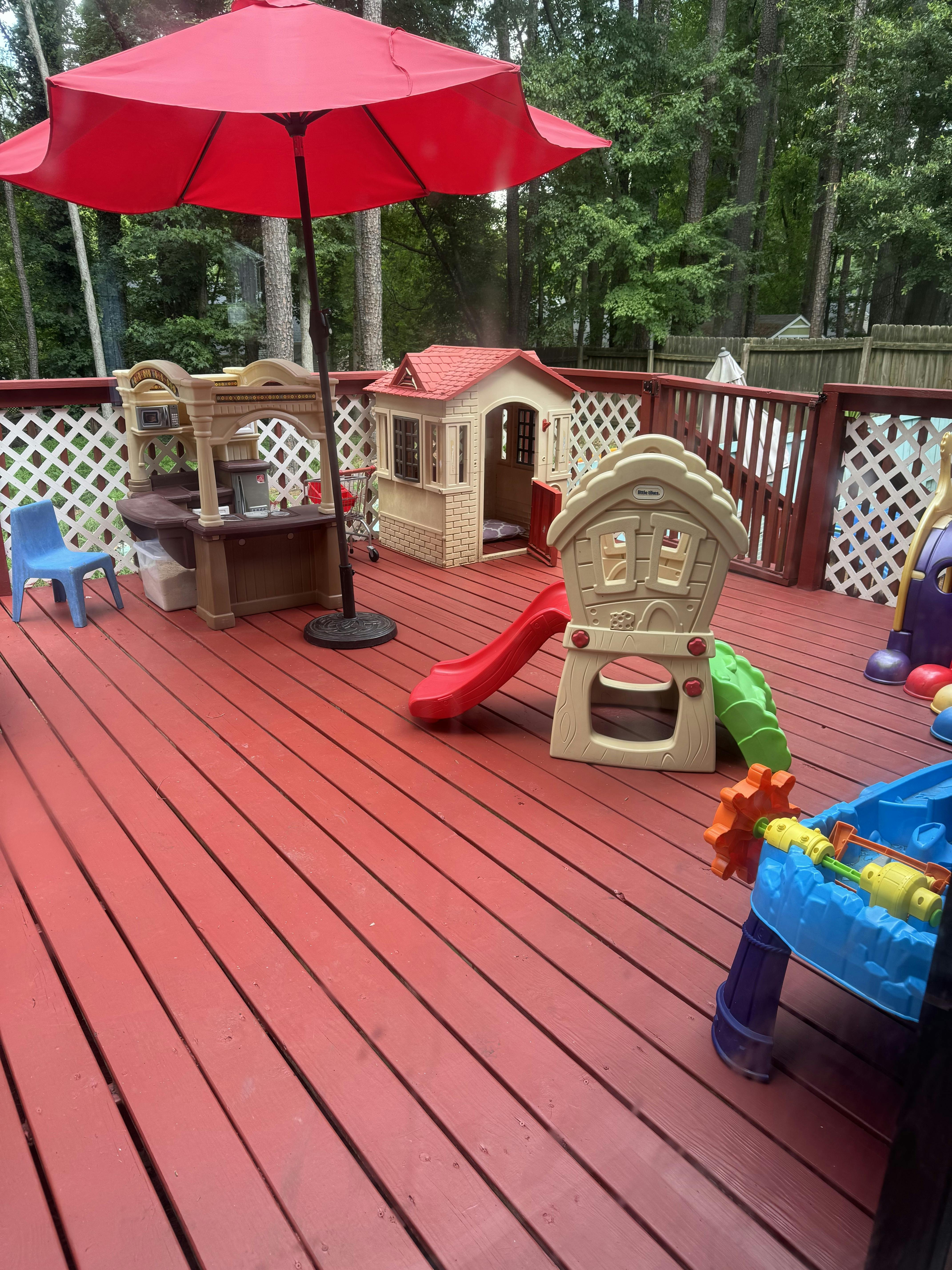Red deck with children's playhouses, slide, and umbrella