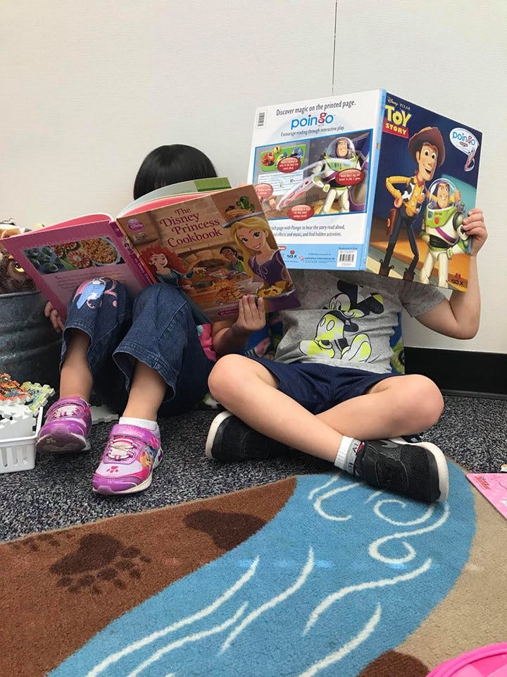 Two children sitting on the floor reading books