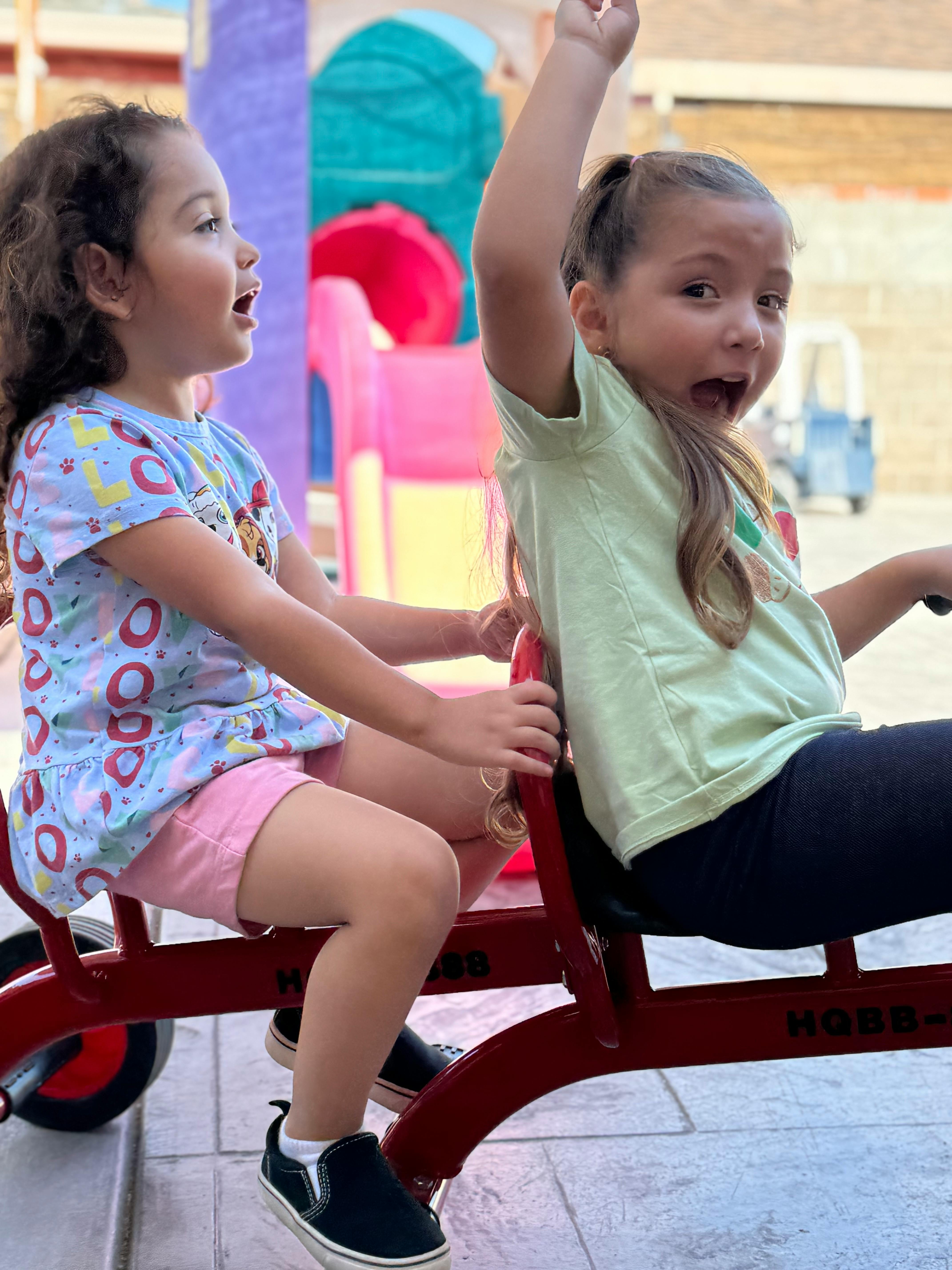 Two children riding a red tandem tricycle