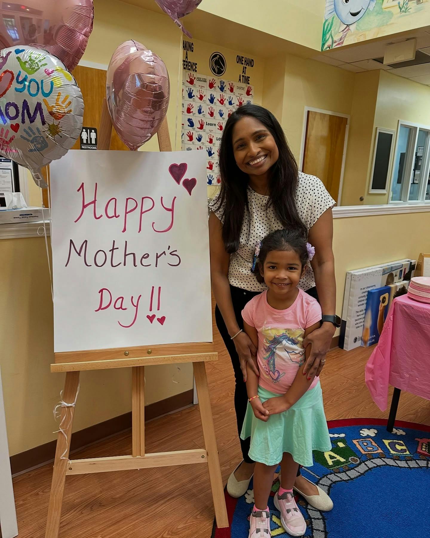 Person and child standing next to a Happy Mother's Day sign