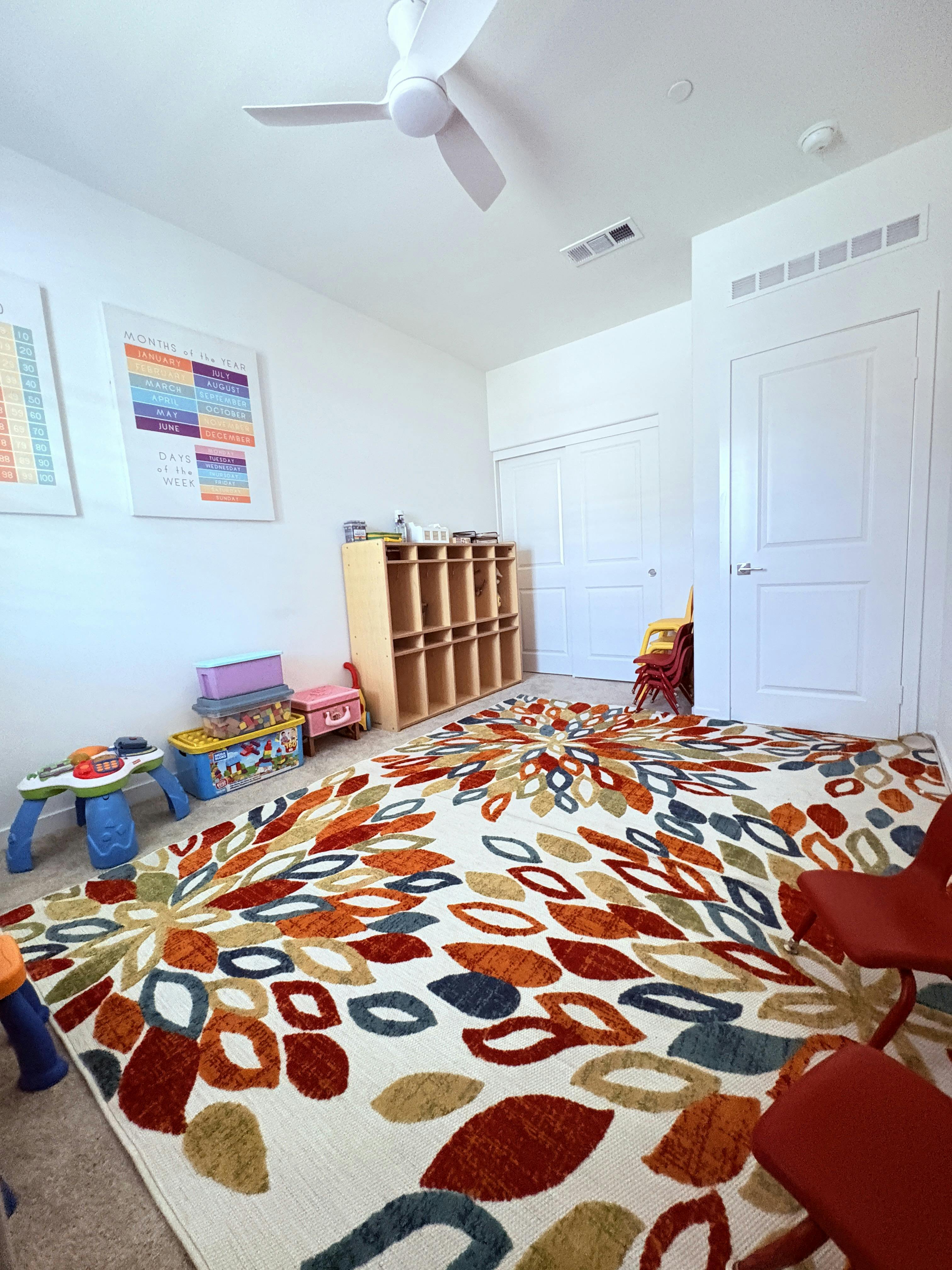 Playroom with a colorful floral rug, storage cubbies, and toys