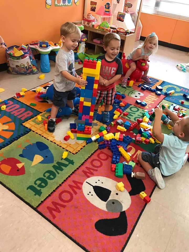 Children playing with colorful building blocks on a rug