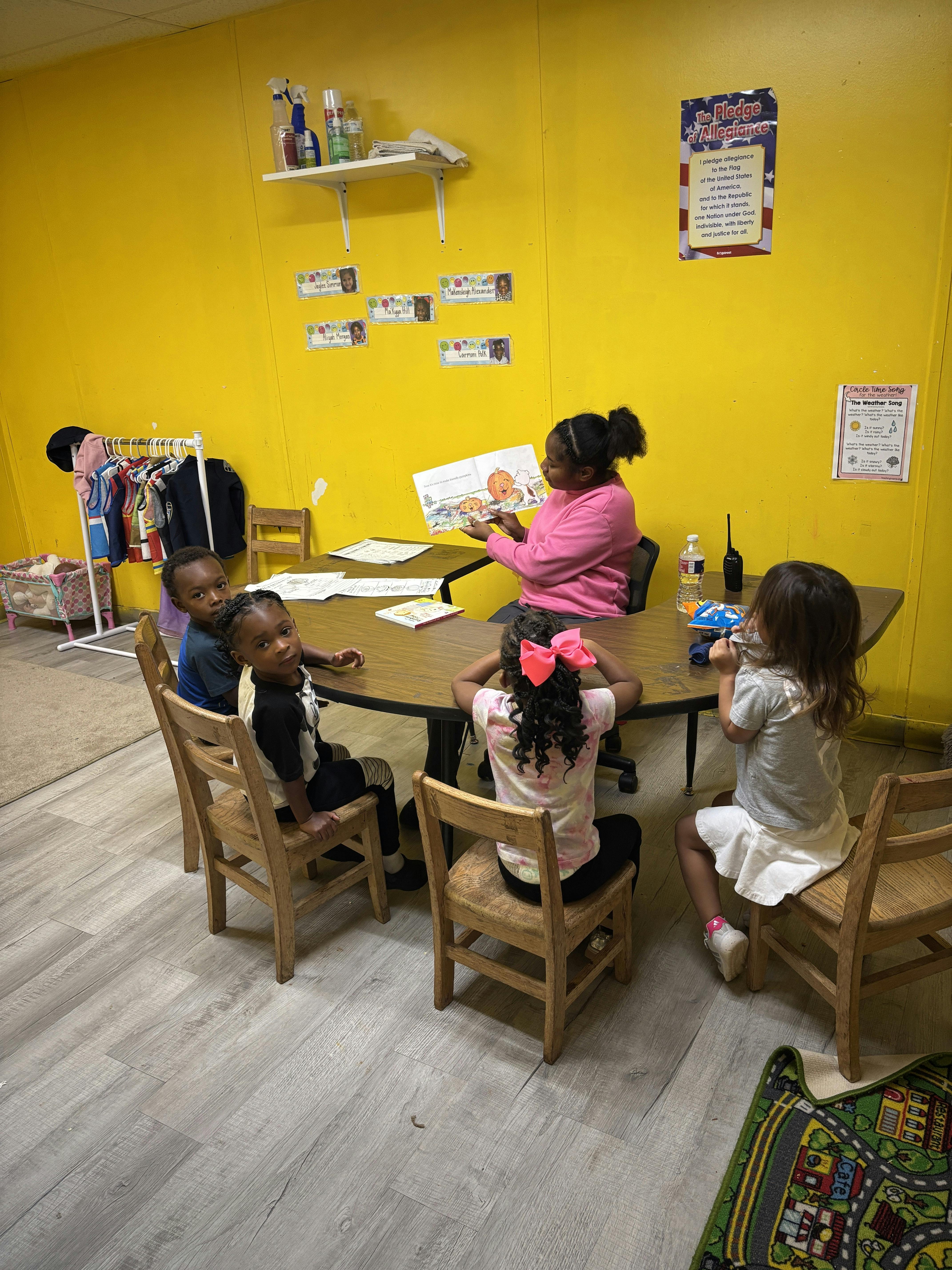 Adult reading a book to children seated around a table in a classroom