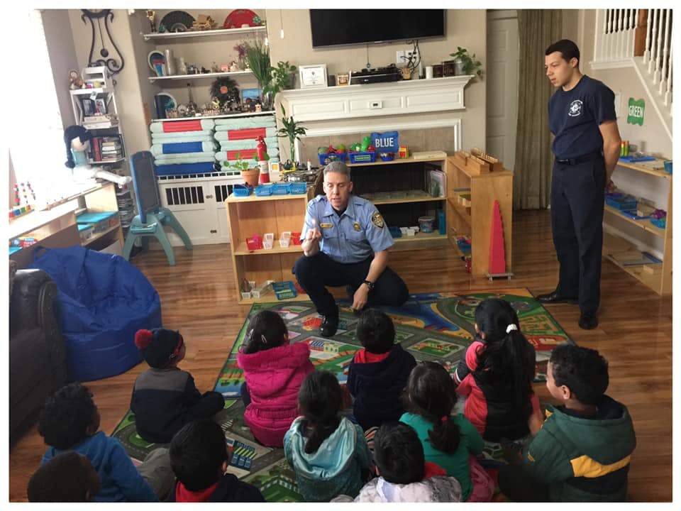 Two people in uniform speaking to a group of children in a classroom