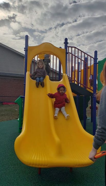 Two children on a yellow playground slide
