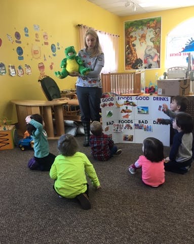 Person holding two frog puppets in front of children
