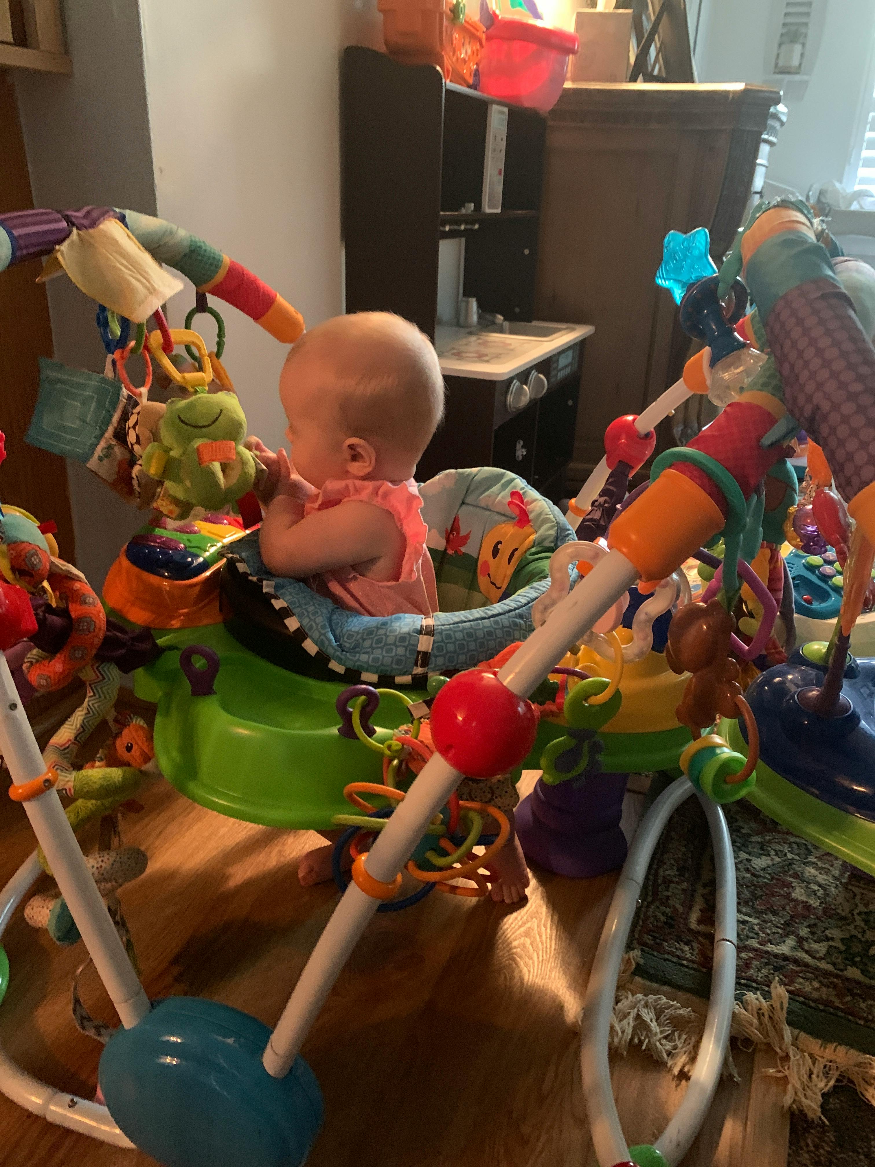 Child in a baby bouncer surrounded by toys