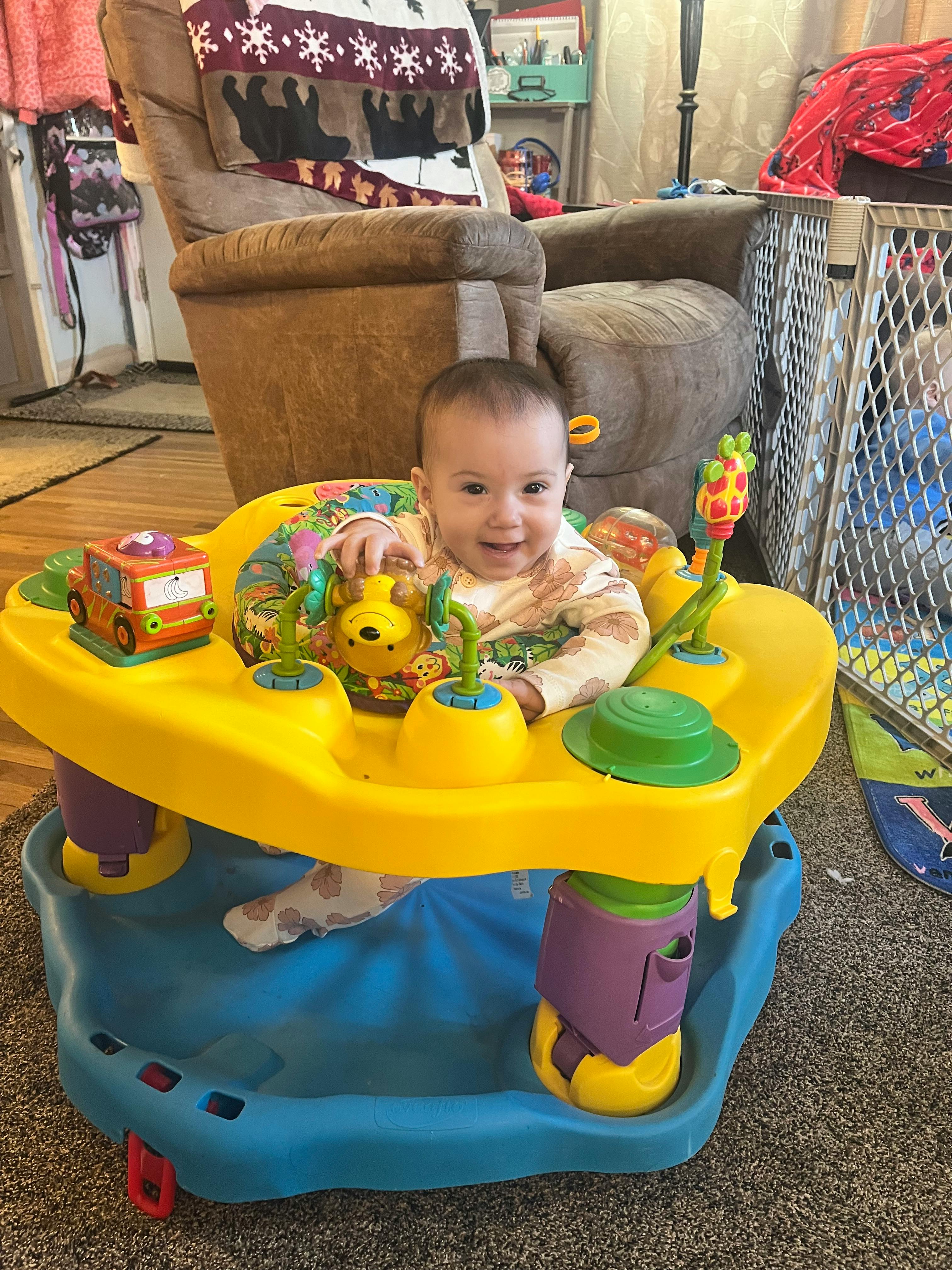 Child in a yellow and blue activity center with toys