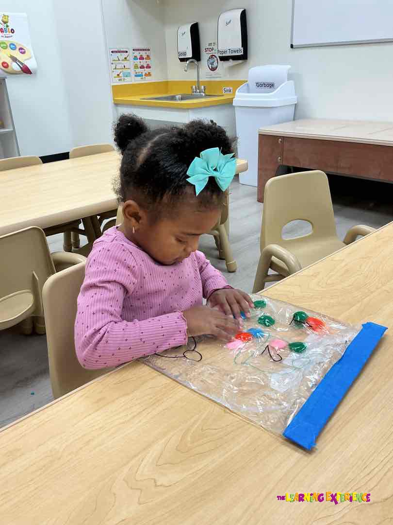 Child playing with a clear sensory bag on a wooden table in a classroom