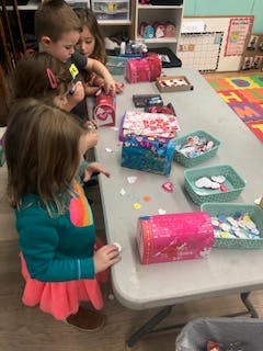 Children decorating boxes at a table