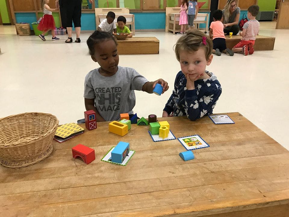 Two children playing with colorful blocks at a table