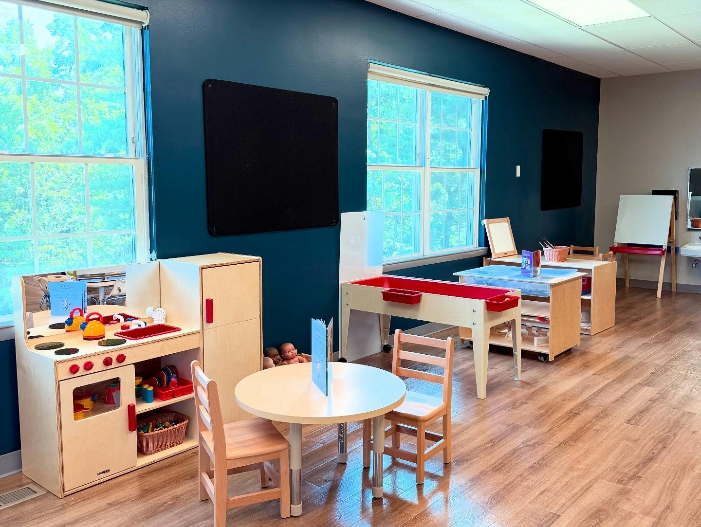 Children's play kitchen and tables in a room with blue walls