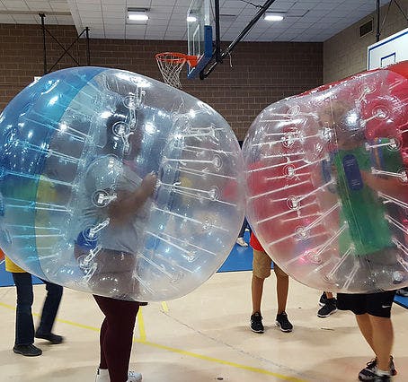 People in large inflatable bubble suits in a gym