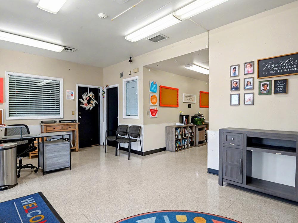 A waiting room with chairs, a desk, and framed pictures on the wall