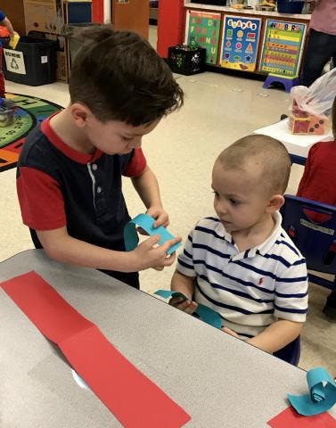 Two children at a table making paper crafts