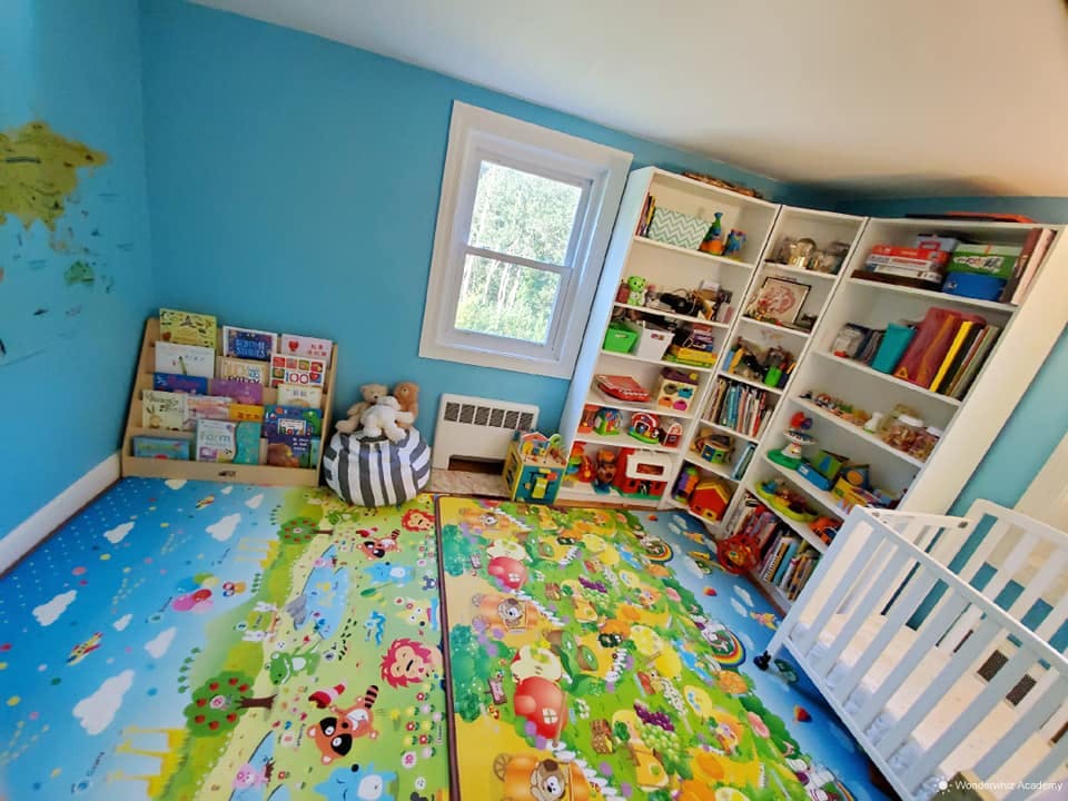 Child's room with colorful playmats, bookshelves, and a crib