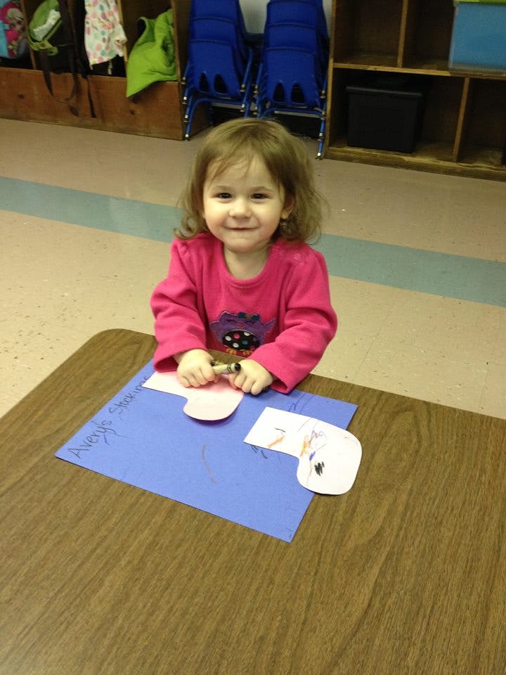 Child sitting at a table with paper and a marker