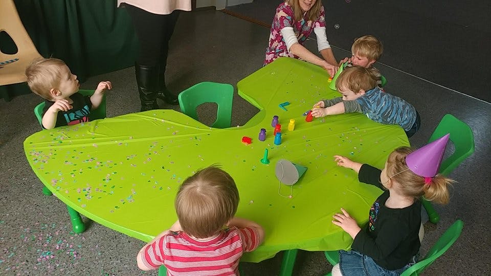Children playing with colorful pieces at a green table