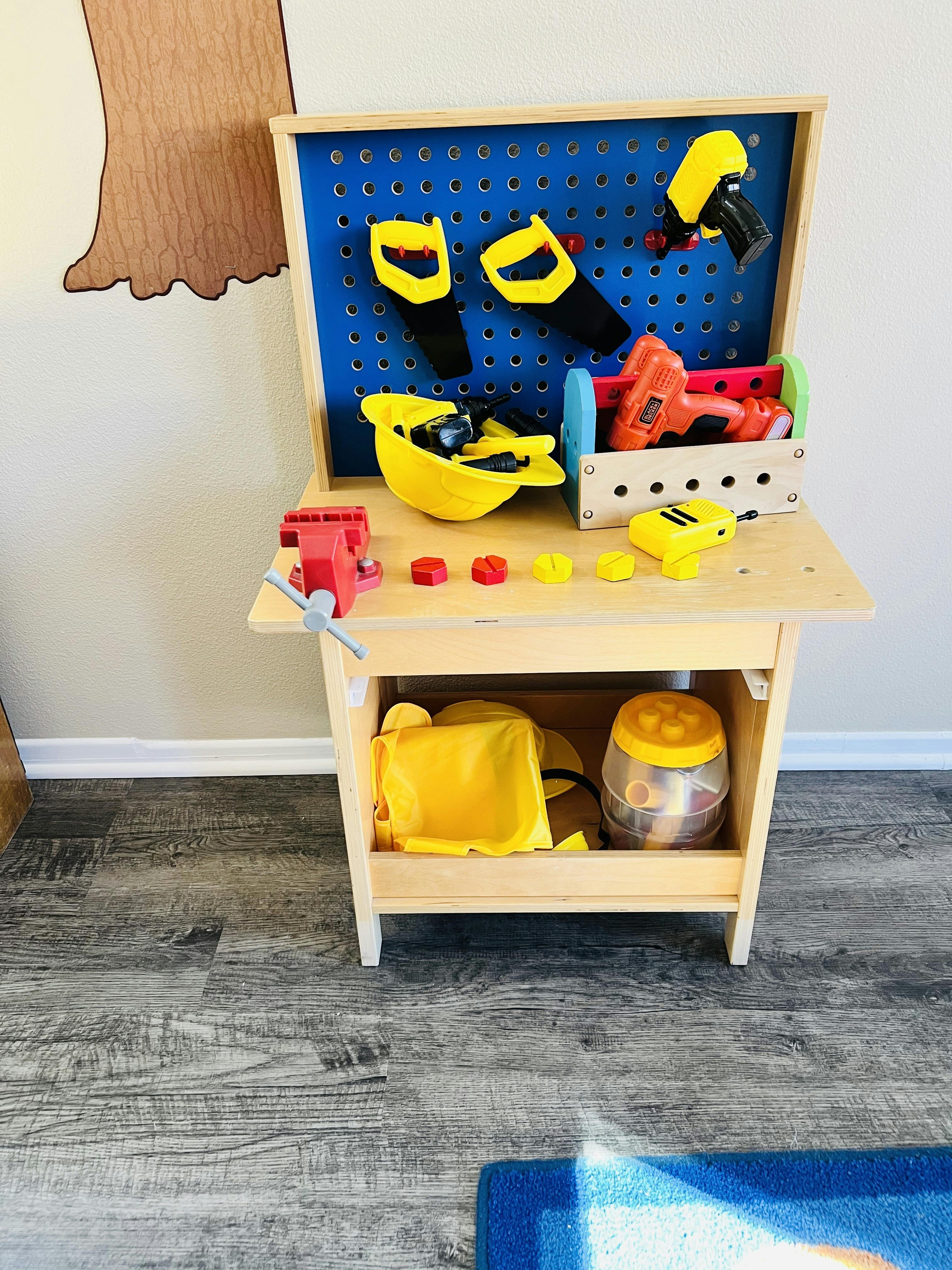 Child's play workbench with tools, including saws, drills, and a hard hat